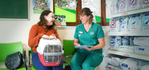 Client with pet on her lap in carry cage while talking to vet